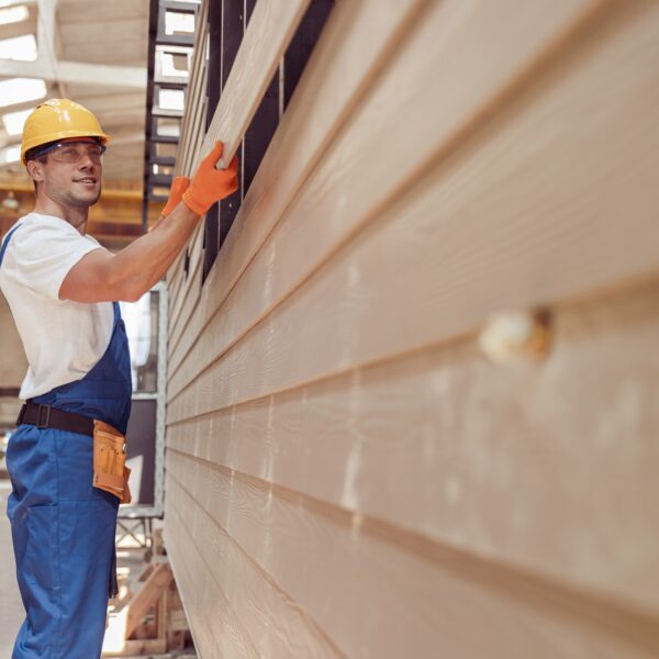 Cheerful worker building module house at construction site